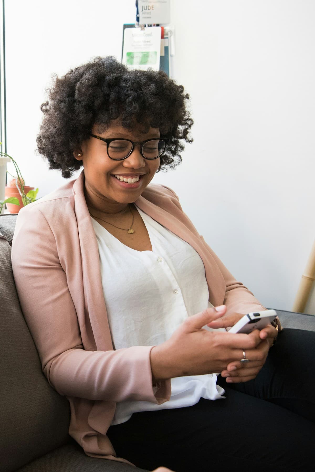 A dark-skinned woman smiling while using her smartphone